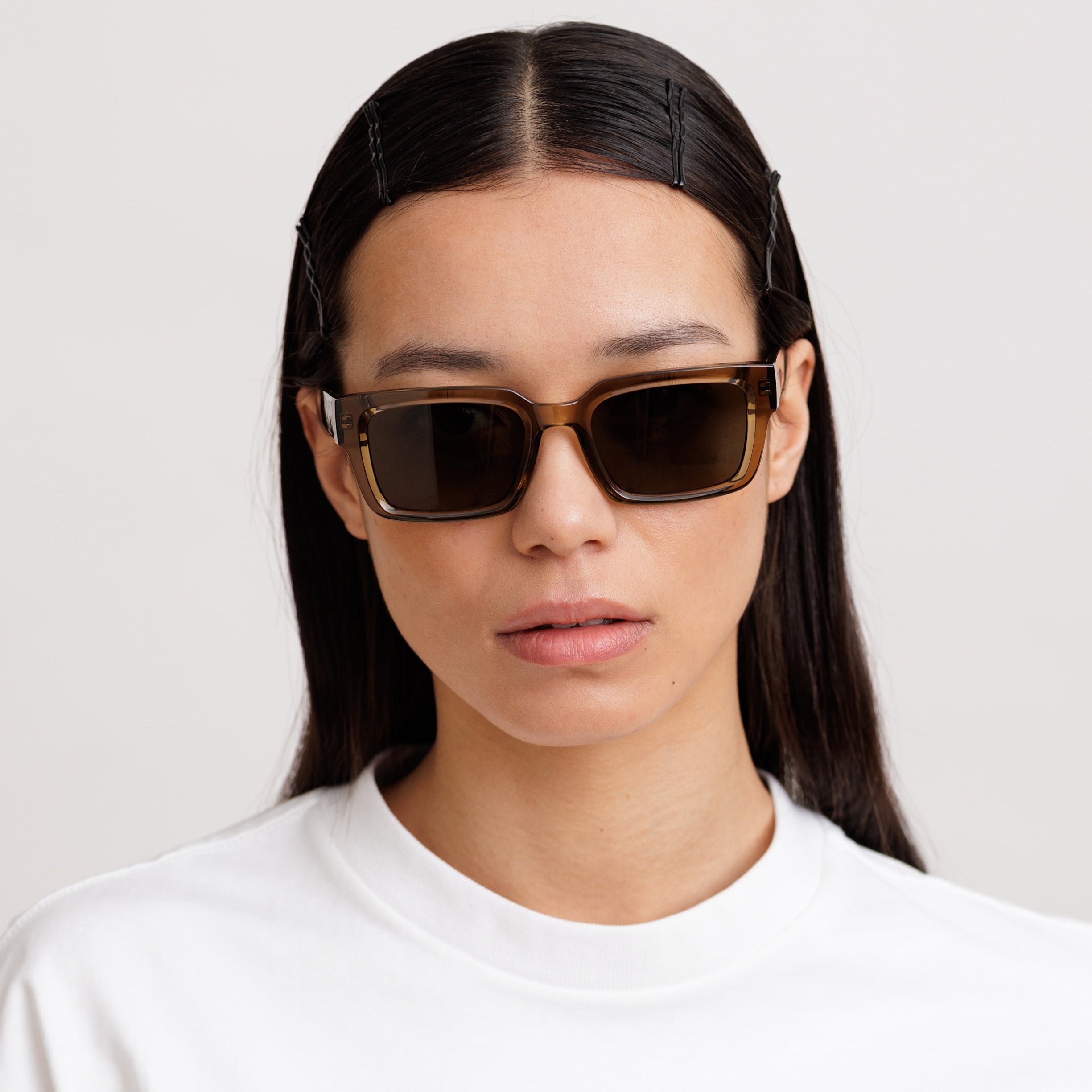 Woman wearing green sunglasses with a plain background