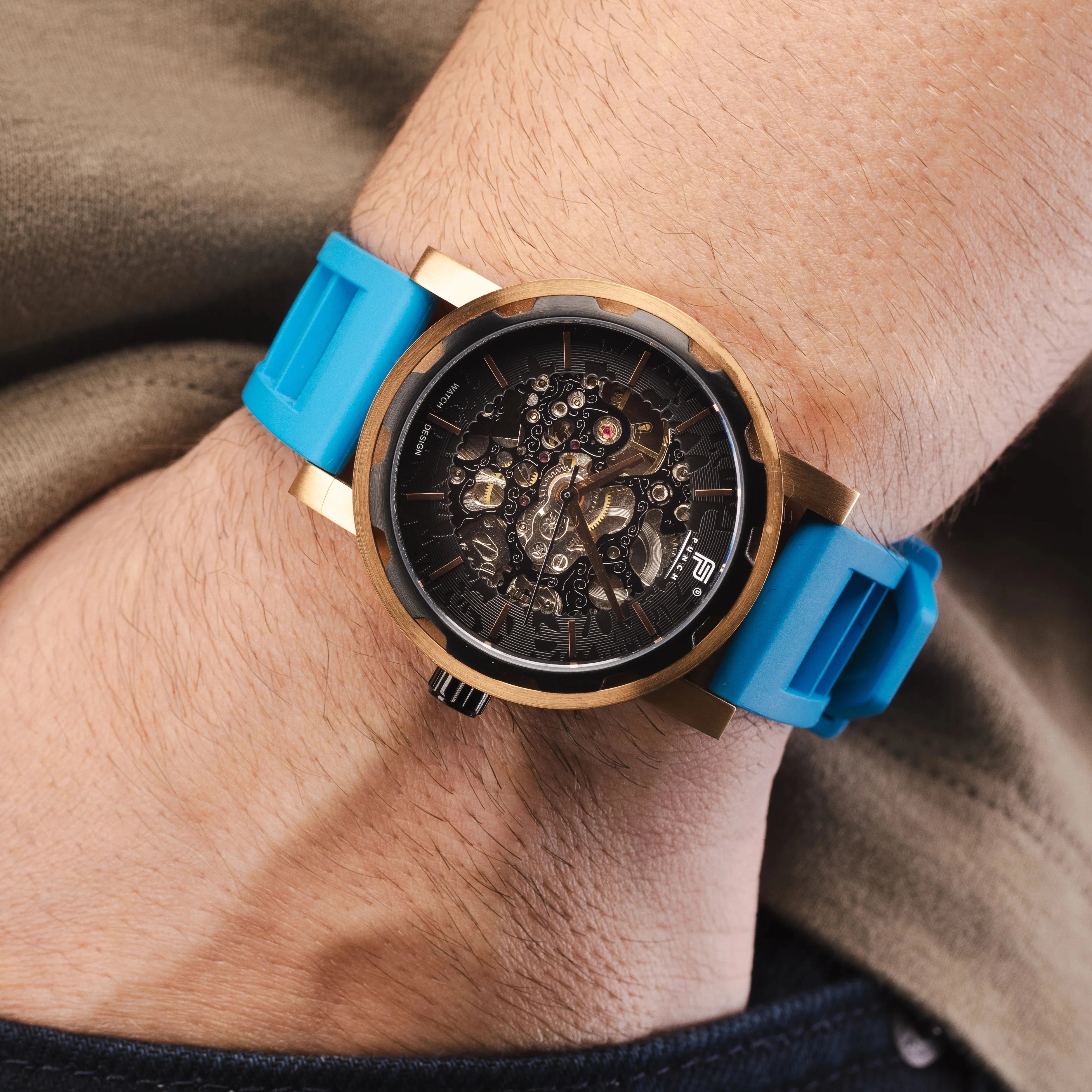 man wearing rose gold and black punch watch with a blue rubber strap